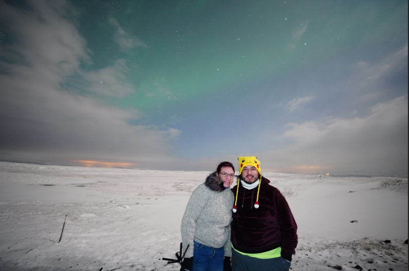 Alex and Jessica standing under the northern lights in Iceland